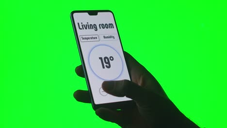 on-the-green-background-of-the-chromakey-a-man-controls-the-temperature-and-alarm-systems-via-an-app-on-his-mobile-phone