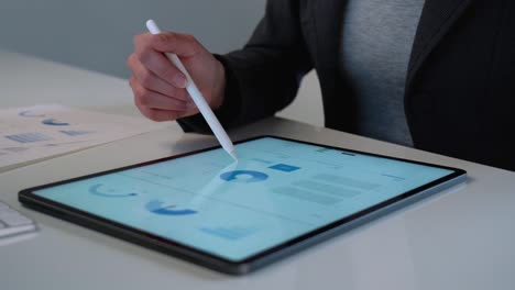 Business-woman-working-on-tablet-computer-and-analyzing-a-marketing-report-on-white-desk