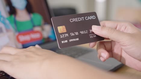 Close-up-consumer-woman's-hand-holding-credit-card-making-e-bank-online-payment-for-purchase-in-online-website-store-with-laptop-computer.-Ecommerce-website-payments.-new-normal-digital-lifestyle