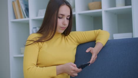 Mujer-usando-el-teléfono-inteligente.-Chica-bonita-usando-la-pantalla-de-toque-del-teléfono-inteligente-moderno-y-sonriendo-en-casa