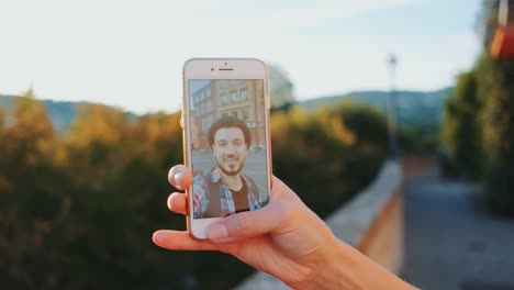 Close-up-of-woman's-hand-holding-smartphone-and-providing-video-call-with-man