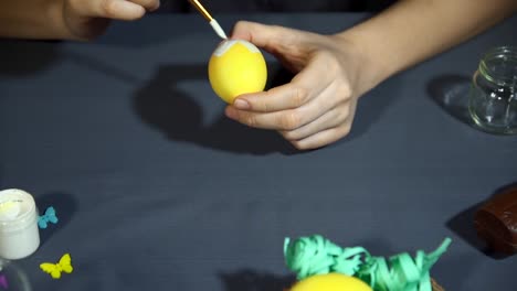 Female-hands-painting-the-egg-decoration-for-easter-over-a-gray-background.