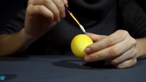 Female-hands-painting-the-egg-decoration-for-easter-over-a-gray-background.