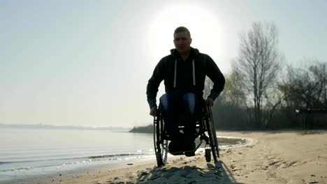 Man-with-disabilities-rides-along-beach-in-wheelchair