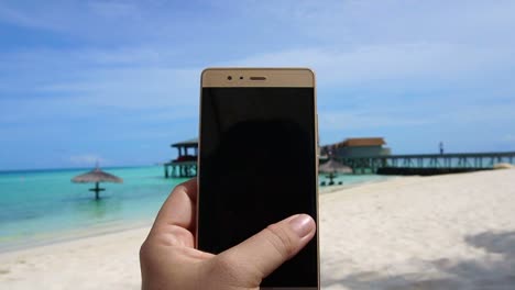 POV-shot-of-a-smart-phone-taking-photo-in-tourist-hand.-Having-fun-at-ocean-vacation