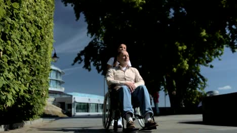 Pleasant-volunteer-pushing-a-wheelchair-of-an-aged-man