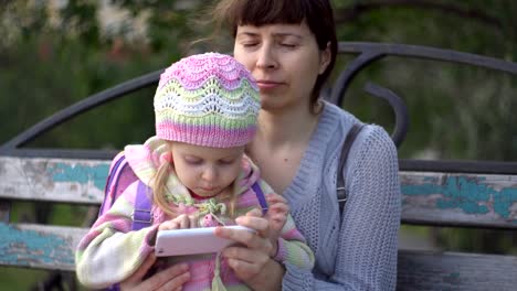 Madre-e-hija-usando-teléfono-fuera-una-noche-fría