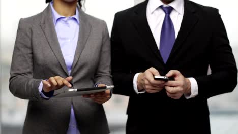 empresario-y-empresaria-con-smartphones-en-oficina