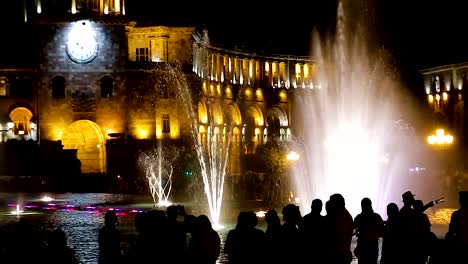 Los-turistas-observan-fuente-Musical-cerca-Gobierno-gran-edificio,-reloj-de-datación