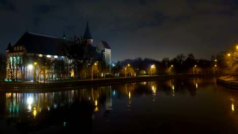 Illumination-on-a-historic-building.-Historic-Landmark.-Time-lapse.-Cathedral-of-Kant-in-Kaliningrad.-Old-medieval-castle-at-night-against-the-sky.-Timelapse.-City-park-with-a-river,-a-pond.