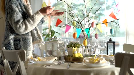 Young-woman-setting-easter-festive-table-with-bunny-and-eggs-decoration