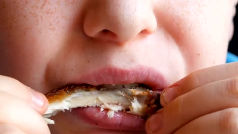 Close-up-view-of-teenager's-mouth,-camera-approaching.-A-boy-with-an-appetite-eats-fried-chicken-wing-in-a-fast-food-restaurant