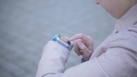 Closeup-tilt-up-shot-of-mixed-race-student-girl-using-smartwatch-and-smiling-near-univercity-at-street