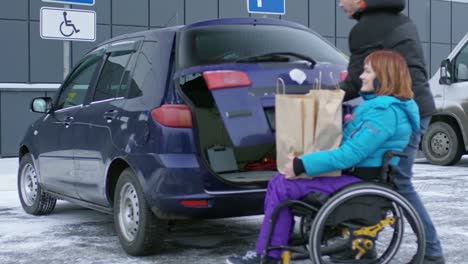 Hombre-cargando-bolsas-en-el-coche-con-mujer-parapléjico