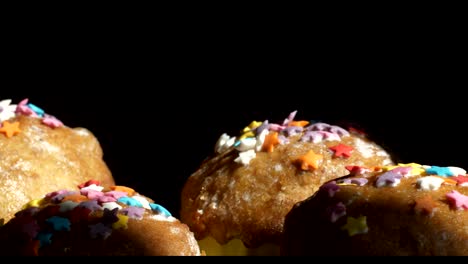 Easter-cakes-with-a-colored-sprinkle-stand-in-a-row-on-a-black-background