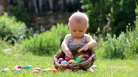 Cute-child,-playing-with-little-bunny-and-easter-eggs-in-a-blooming-garden,-springtime.-Boy-play-with-rabbit,-egg-hunting-for-holiday