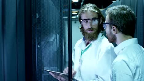 Two-IT-engineers-are-working-in-a-data-center.-They-are-discussing-their-work.-Shot-on-RED-EPIC-Cinema-Camera--in-Slow-Motion-.