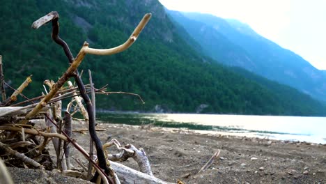 Young-riders-on-horseback-wander-along-the-sandy-shore-of-a-mountain-lake.