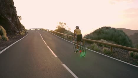 Radfahrer-sitzen-auf-einem-Fahrrad-auf-einem-Smartphone-für-social-Networking-Berglandschaft-bei-Sonnenuntergang-fotografieren.-Slow-motion