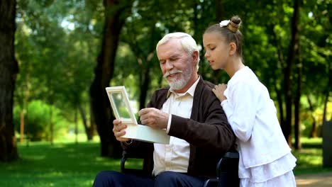 Grandfather-in-wheelchair-showing-granddaughter-military-token,-telling-stories