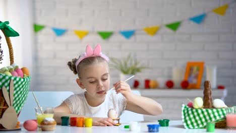 Left-handed-girl-brushing-Easter-eggs-with-paint,-creativity,-childrens-hobby