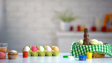 Funny-girl-appearing-from-under-table-and-excitedly-looking-at-dyed-Easter-eggs