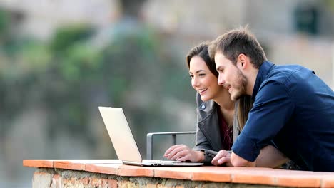 Pareja-feliz-viendo-el-contenido-del-ordenador-portátil-en-un-balcón