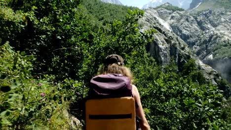 Turista-de-caminante-de-trepador-mujer-con-una-mochila-en-la-caminata-va-a-lo-largo-de-la-ruta-del-telón-de-fondo-hermosos-paisajes