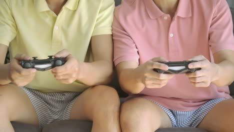 Competitive-young-asian-gay-couple-push-and-shove-each-other-as-they-play-a-video-game-at-home