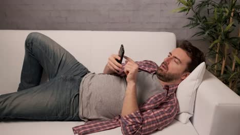 Sleepy-man-using-smartphone-on-the-couch