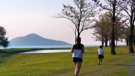 Eine-fette-asiatische-Frau-joggt-abends-in-natürlichem-Sonnenlicht,-zusammen-mit-seinem-Sohn-läuft.--Für-gute-Gesundheit.-Zeitlupe