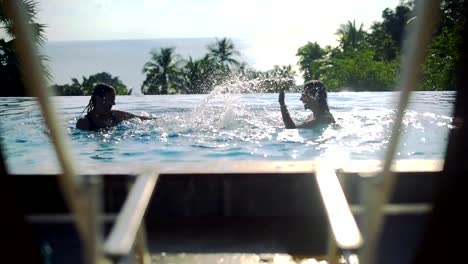 Two-girls-playing-in-the-outdoor-pool-on-a-sunny-day-on-a-tropical-island