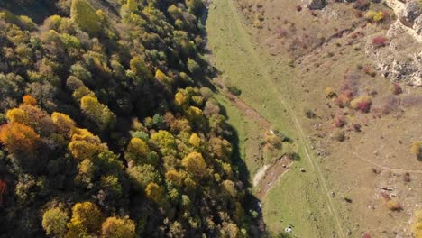 Luftaufnahme-eines-kleinen-Flusses,-der-an-einem-warmen-Herbsttag-entlang-einer-wunderschönen-Schlucht-fließt