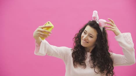 Beautiful-young-girl-standing-on-a-pink-background.-During-this,-there-are-ears-of-rabbits-on-the-head.