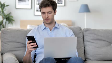 Hombre-joven-guapo-usando-Smartphone-para-el-trabajo,-sentado-en-el-sofá