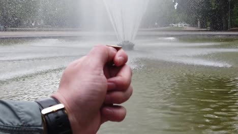 Männliche-und-weibliche-Hand-wirft-eine-Münze-in-den-Brunnen-für-viel-Glück.