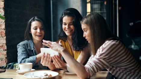 Fröhliche-Mädchen-Blick-auf-Smartphone-Bildschirm-wischen-lächelnd-Spaß-im-Café