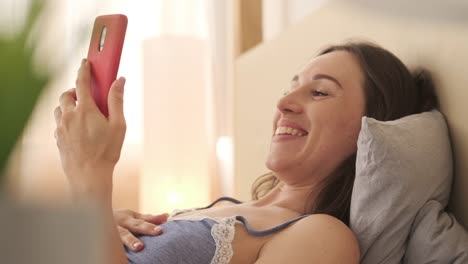 Emocionada-mujer-video-chating-usando-el-teléfono-móvil-en-la-cama