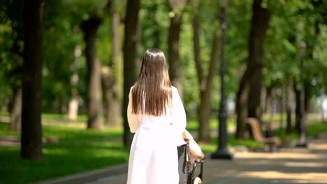 Mujer-voluntaria-caminando-con-paciente-discapacitado-en-el-parque-del-hospital,-vista-trasera