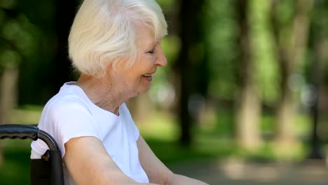 Smiling-nurse-communicating-with-retired-woman-in-wheelchair-and-supporting-her