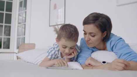 Happy-family-mother-and-child-son-with-tablet-in-evening.-Happy-family-mother-and-child-son-with-tablet-in-evening-before-bed.