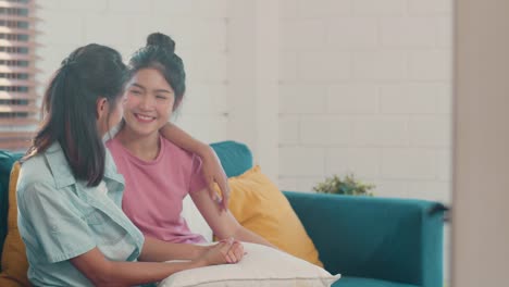 Young-Asian-Lesbian-couple-hug-and-kiss-lying-sofa-in-living-room-at-home.