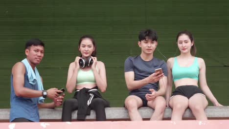 Asian-young-men-and-girl-relexing-exercise-after-sport-running-Peple-use-smartphone-play-app-music