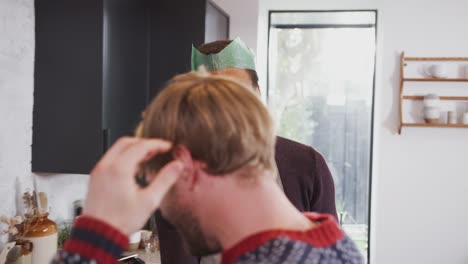 Pareja-masculina-gay-en-casa-bailando-en-la-cocina-mientras-preparan-la-cena-el-día-de-Navidad-juntos