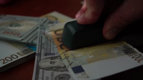 The-stapler-fastens-the-dollar-and-euro-notes-with-iron-clips.-Stapler-with-paper-clips-on-the-background-of-banknotes.-Counterfeit-money