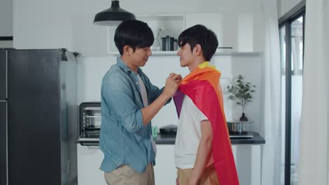 Asian-Gay-couple-standing-and-hugging-room-at-home.-Young-handsome-LGBTQ+-men-kissing-happy-relax-rest-together-spend-romantic-time-in-modern-kitchen-with-rainbow-flag-at-house-in-the-morning-concept.