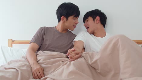 Schöne-asiatische-homosexuell-Paar-im-Bett-zu-Hause-sprechen.-Junge-asiatische-LGBTQ-+-Kerl-glücklich-entspannen-zusammen-verbringen-romantische-Zeit-nach-dem-Aufwachen-im-Schlafzimmer-im-modernen-Haus-im-Morgen-Konzept.