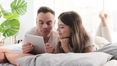 Couple-using-digital-tablet-in-bed