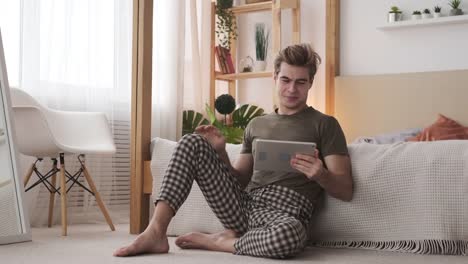 Man-using-digital-tablet-in-bedroom