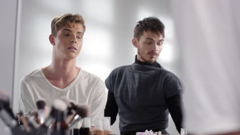 Artista-de-maquillaje-masculino-haciendo-selfie-con-modelo-masculino